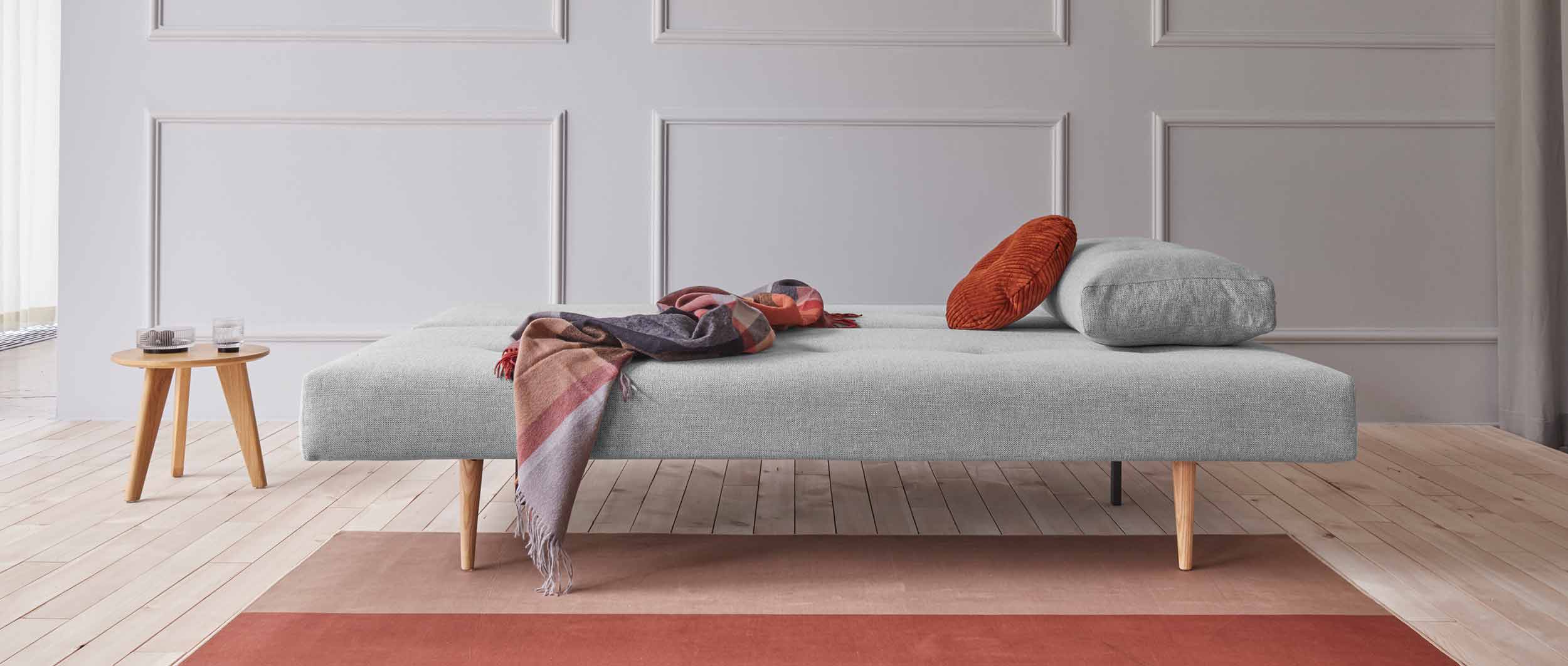 Das RECAST PLUS Schlafsofa mit hellen Styletto Holzfüßen in der Bettposition (Bett ca. 140x200 cm)
