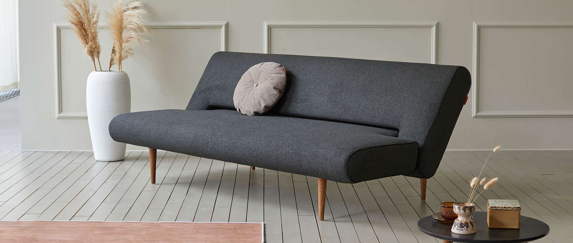 Das UNFURL Schlafsofa in der Relaxposition mit dunklen Styletto Holzfüßen