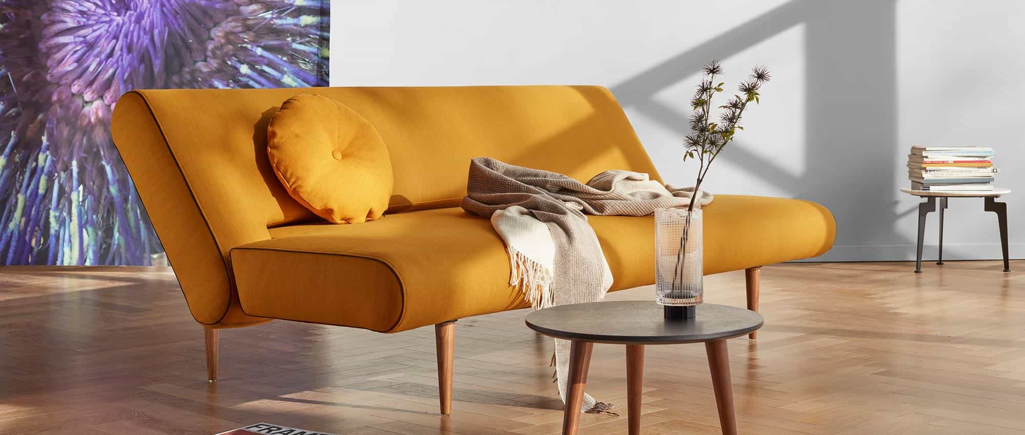 Das UNFURL Schlafsofa als Sonderanfertigung im Stoff Elegance Burned Curry (507) mit einem CIRCLE Kissen und STYLO Tisch