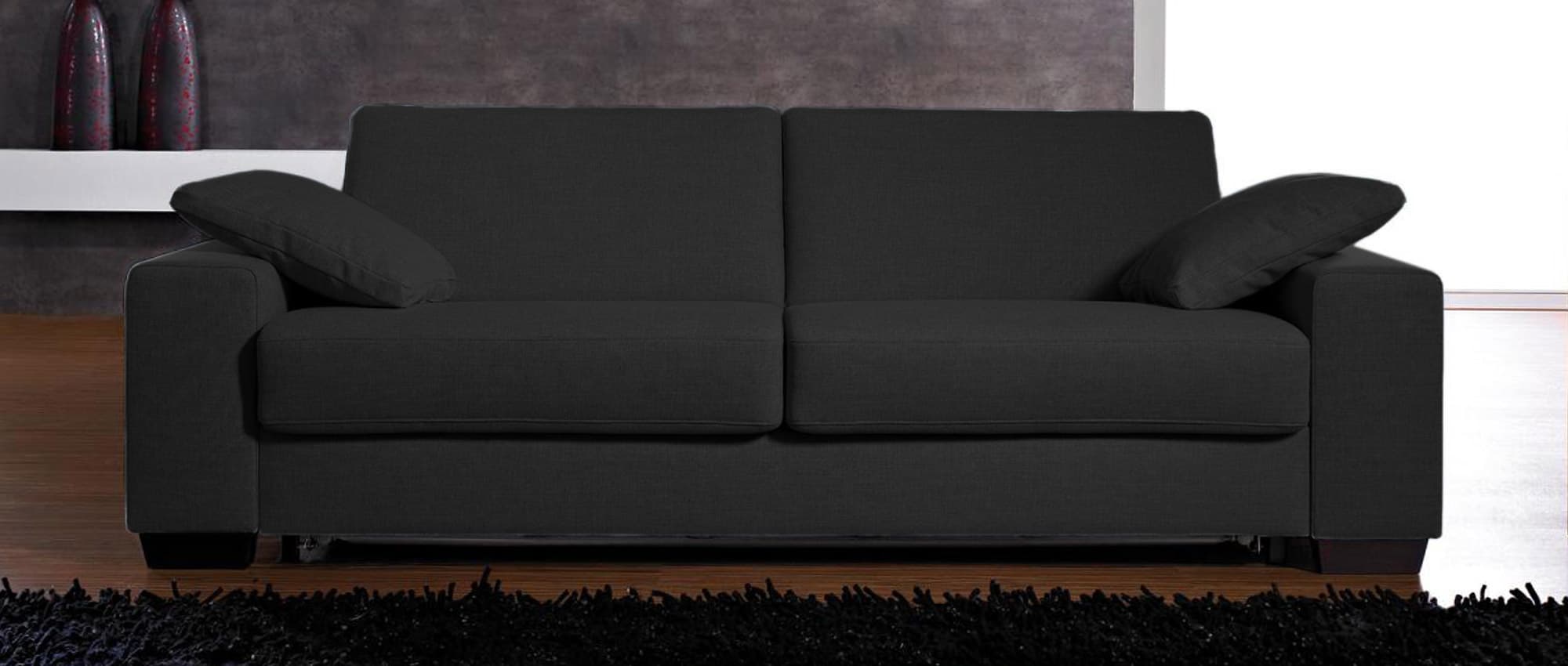 Das AMSTERDAM DELUXE Schlafsofa in einem dunklen Stoff bezogen
