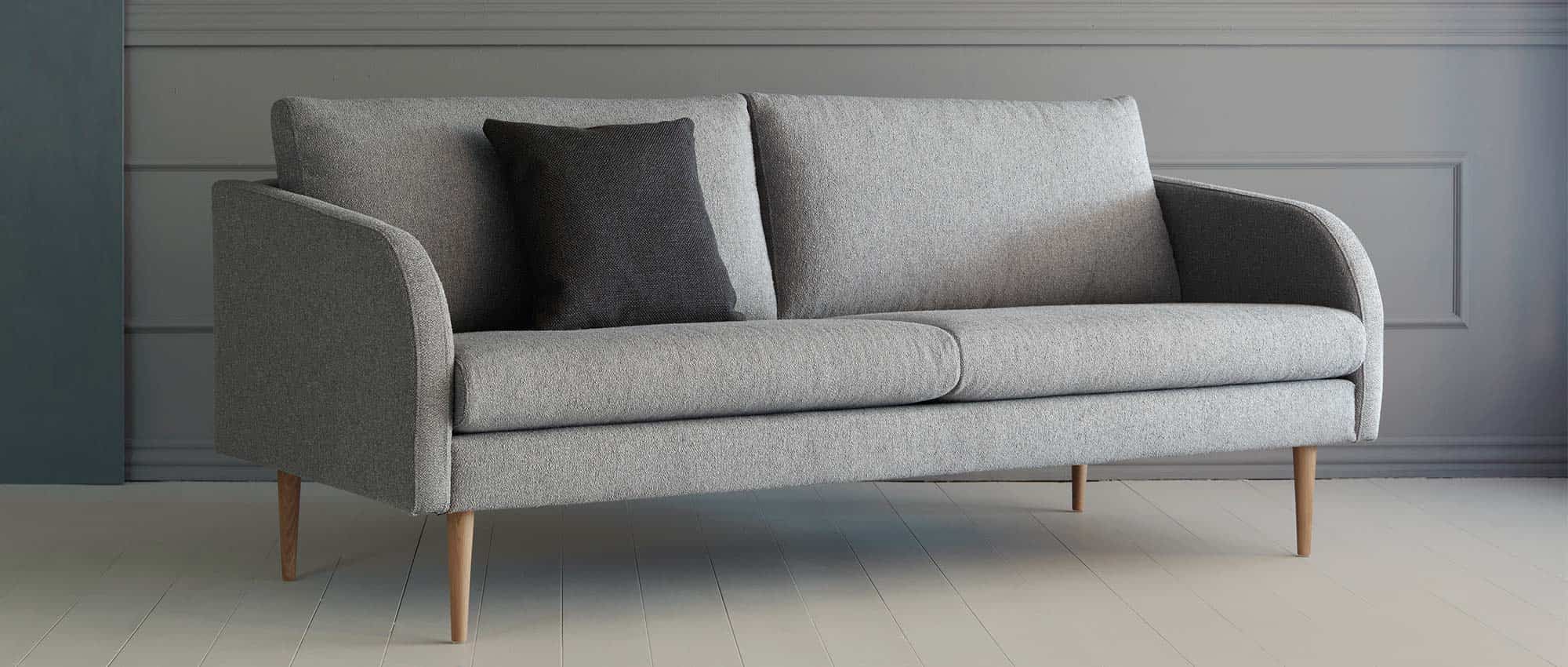 Das BERGEN Designer Sofa mit hell lackierten Eichenholzfüßen - gezeigt am 3-Sitzer Sofa