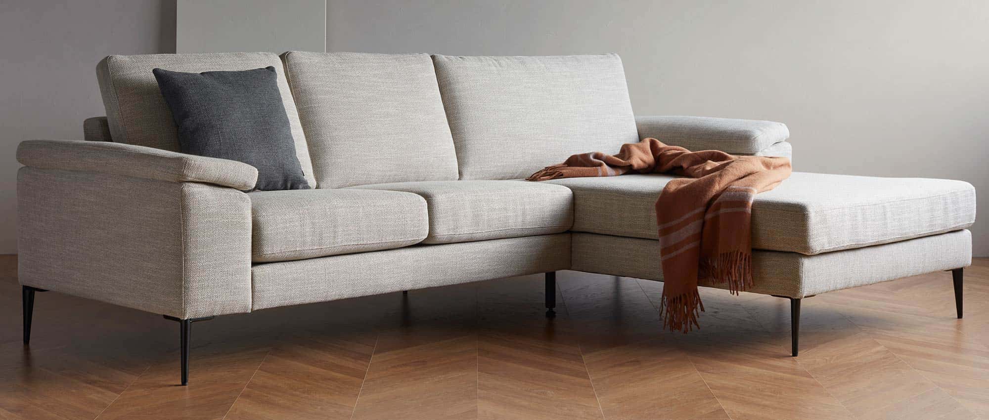 Das Designer Ecksofa TRONDHEIM mit schwarzen Metallfüßen und breiten Armlehnen mit Kissen