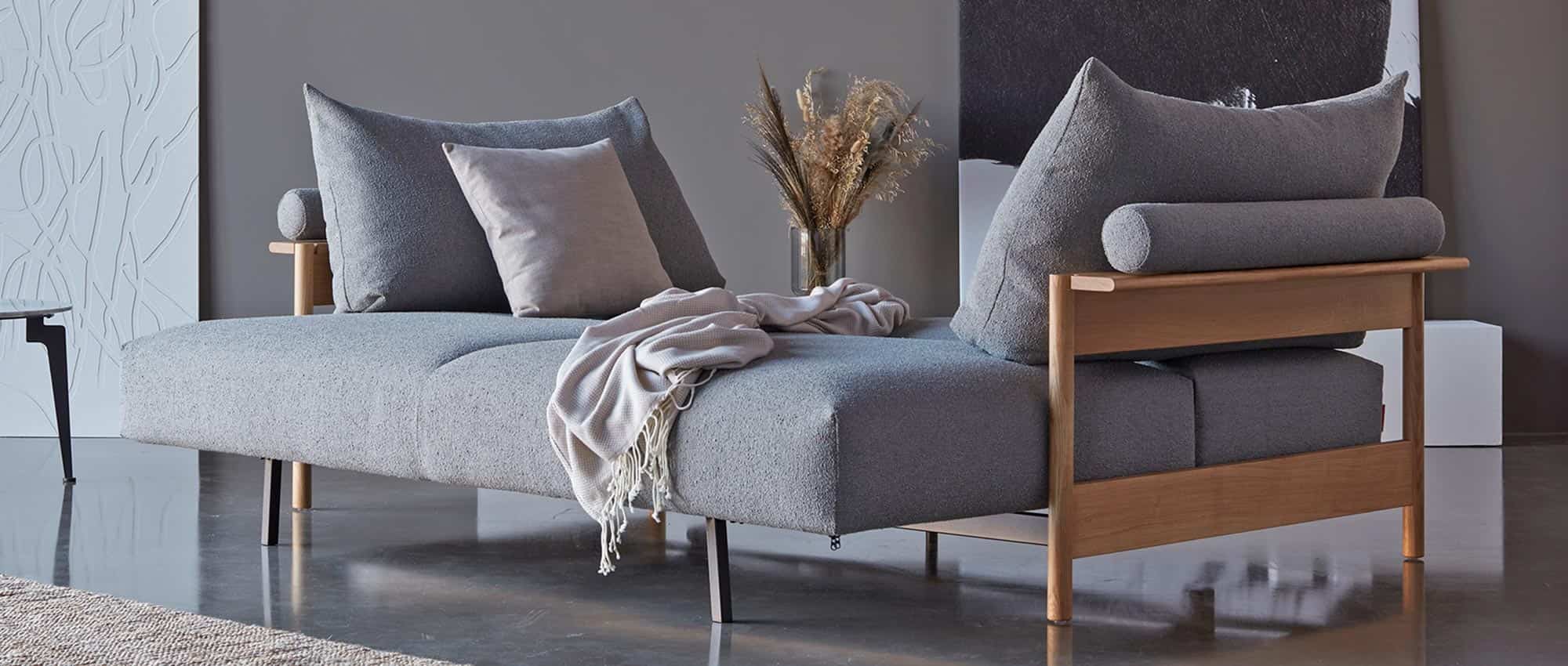 Die großen Rückenkissen des MALLOY WOOD Schlafsofas von Innovation dienen der Unterstützung von Kopf und Nacken - die Nackenrolle ist an den Kissen befestigt