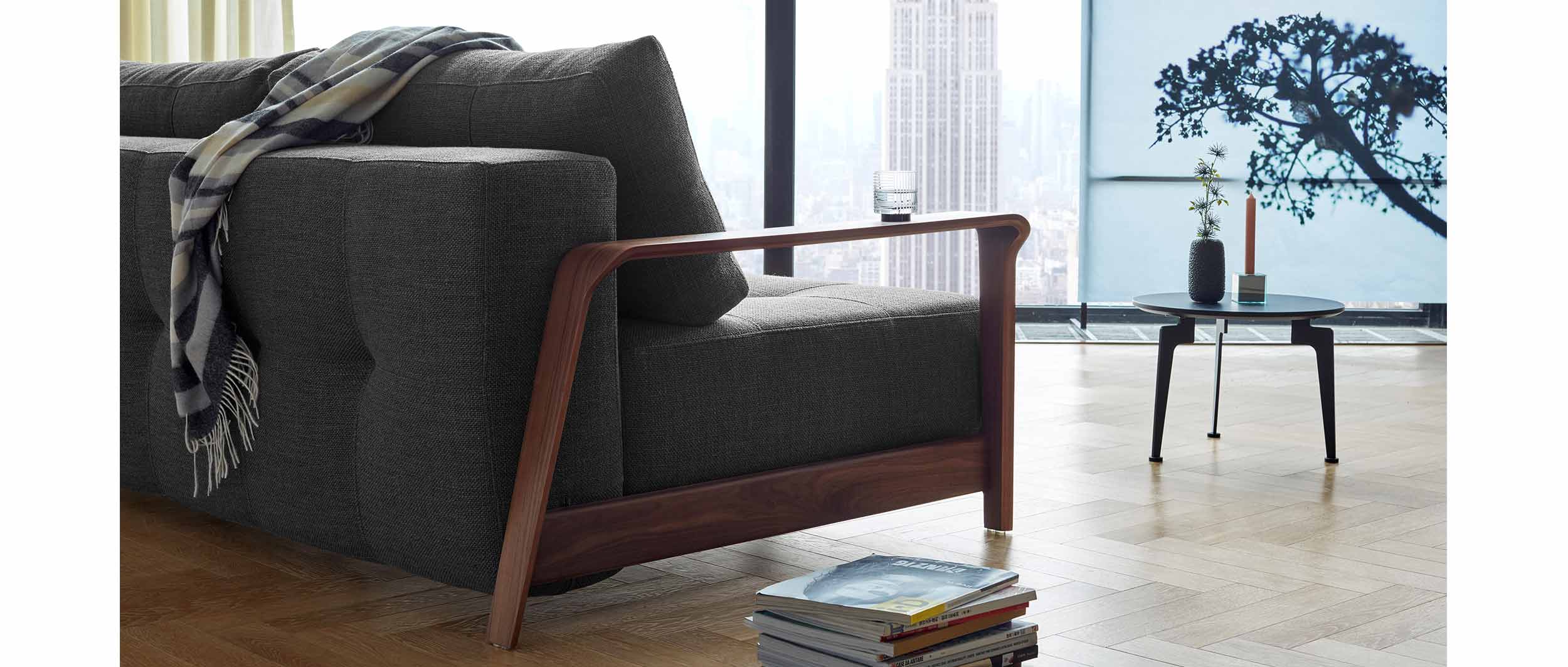 Die dunkelbraunen Armlehnen des RAN DELUXE Schlafsofas sind aus Walnussholz Furnier gefertigt