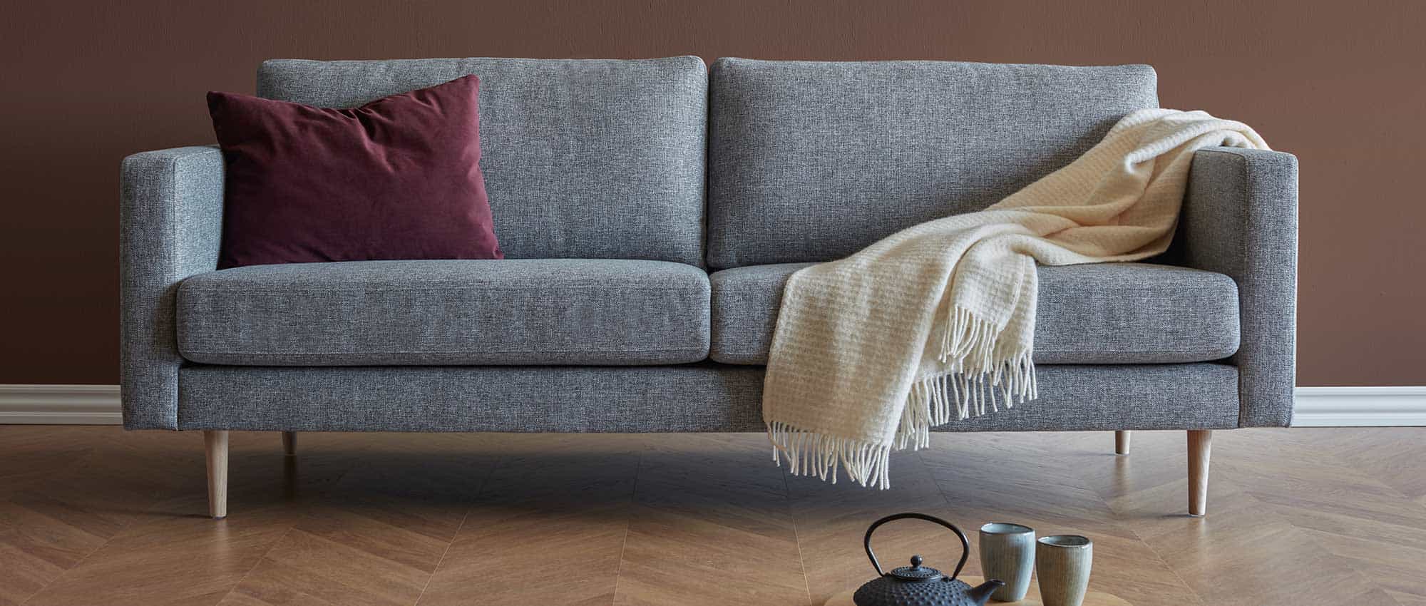 Das TRONDHEIM Sofa hier als 3-Sitzer mit hellen Holzfüßen und schmalen Armlehnen gezeigt - der 3-Sitzer ist separat im Shop erhältlich
